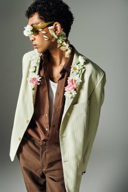 Genç bir Afrikalı Amerikalı şık bir ceketle poz veriyor. Yüzüne ve boynuna çiçekler takıyor..