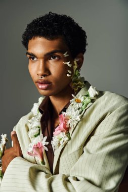 A young African American man poses in a stylish blazer adorned with flowers, showcasing beauty and diversity. clipart