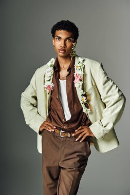 Genç bir Afrikalı Amerikalı, çiçekli bir çelenkle süslenmiş şık bir ceketle poz veriyor..