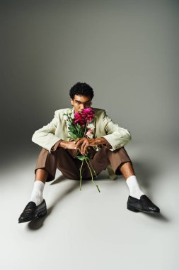 Boynunda çiçekler olan şık, siyah bir adam eşsiz bir moda ve kendini ifade etme tarzı sergiliyor..