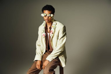 A young African American man poses in a stylish blazer adorned with flowers, radiating confidence and beauty. clipart