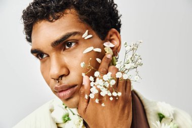 A young African American man poses with flowers on his face and neck, showcasing beauty and diversity. clipart