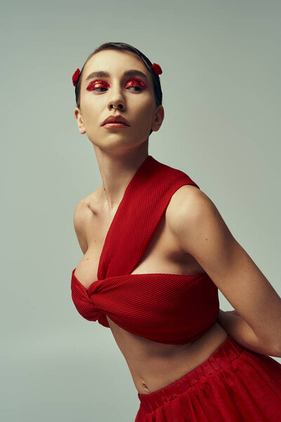 A young woman with short hair poses in a red outfit