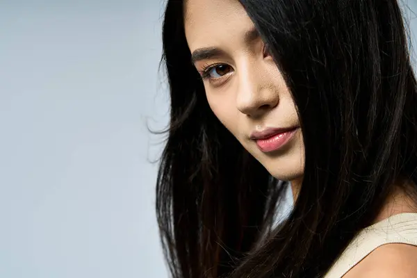 stock image A young woman with long black hair poses confidently, her eyes looking directly at the camera.