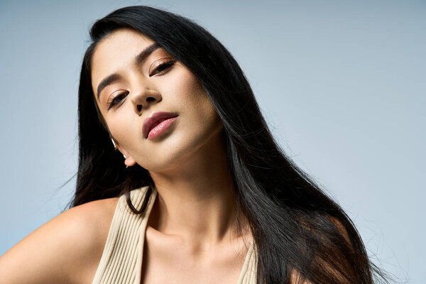 Молодая женщина с длинными темными волосами позирует в студии.
