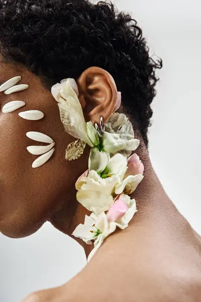 stock image A close-up shot of a young African American man adorned with white and pink flowers, showcasing his beauty and natural grace.