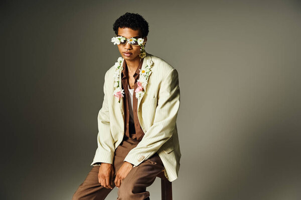 Молодой афроамериканец позирует в стильном блейзере, украшенном цветами, излучающими уверенность и красоту.