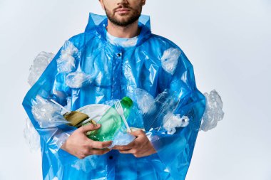 Etrafı plastik atıklarla çevrili bir adam, kirlilik sorununu vurguluyor..