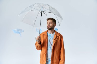 Plastik şekillerle çevrili duran bir adam temiz bir şemsiye tutar..