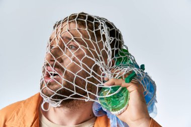 Bir adam plastik bir ağla boğuşuyor, yüzü acıyla kıvranıyor..