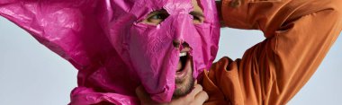 Bir adamın yüzü kısmen pembe plastik bir çarşafla kaplıdır..