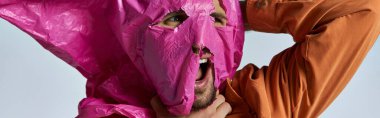 A man's face is partially covered with a pink plastic sheet. clipart