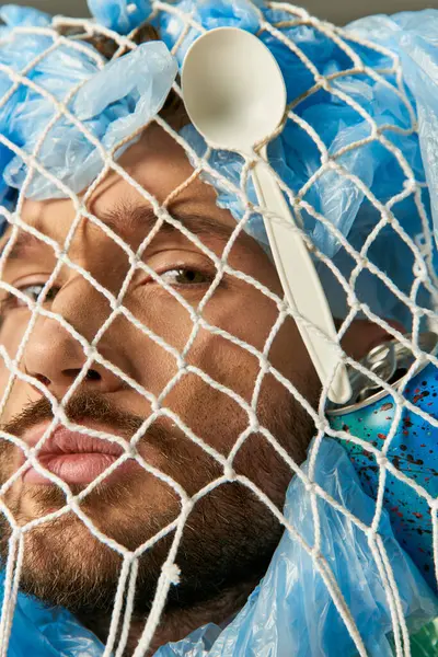 stock image A man's face is partially obscured by a net of plastic bags and a plastic spoon.