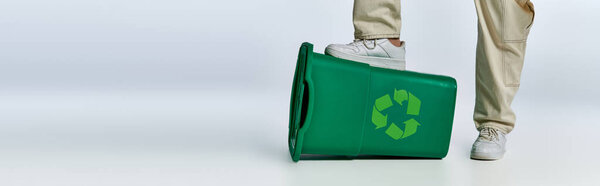 Человек стоит с одной ногой на зеленой мусорной корзине, оставляя свой след на окружающей среде.