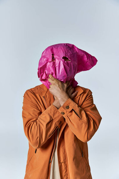 A man wearing a plastic mask, with his hands clasped together.