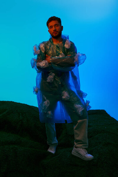A man stands on a stage, his clothes made entirely of plastic bags.