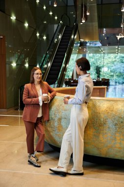 İki meslektaş modern bir ofis lobisinde sohbet ediyorlar, birinin protez bacağı var..