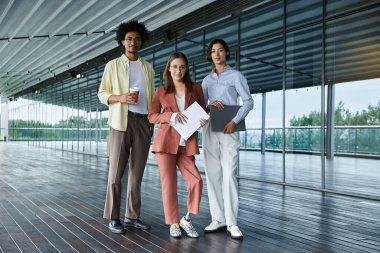 Three colleagues, diverse in ethnicity and abilities, stand together on a modern office rooftop terrace, enjoying a break and conversation. clipart