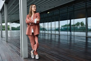Protez bacaklı bir kadın modern ofis terasında bir sütuna yaslanır.