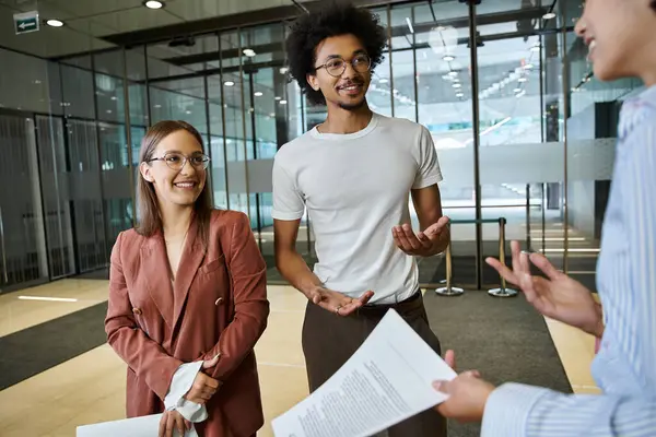 stock image Three colleagues chat amicably in an office lobby, showcasing diversity