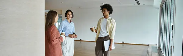 stock image Three colleagues converse and enjoy coffee in a modern office setting.