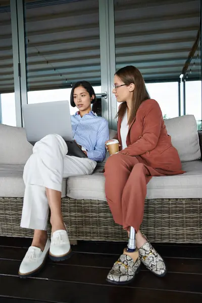 stock image Two colleagues, one with a prosthetic leg, enjoy a casual conversation on a rooftop terrace.