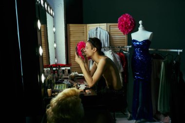 Bir travesti makyaj masasında oturur ve bir performansa hazırlanır..