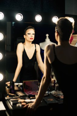 Bir travesti makyaj masasının yanında durur ve bir performansa hazırlanır..