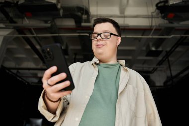 Down sendromlu bir adam telefonuna bakıp gülümsüyor..