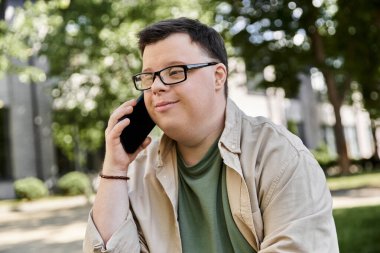 Down sendromlu bir adam dışarıda oturup telefonla konuşuyor..