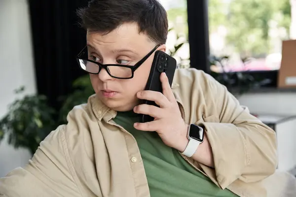 stock image A young man with Down syndrome uses his phone.