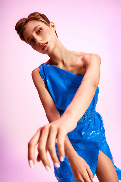 A woman poses in a one-shoulder dress made from recycled materials.