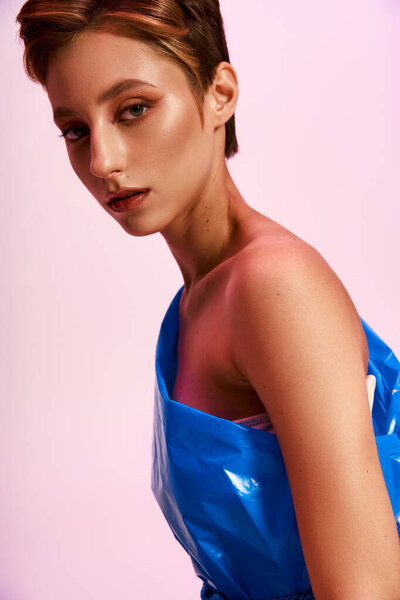 Женщина моделирует одноплечевую вершину из переработанных материалов.