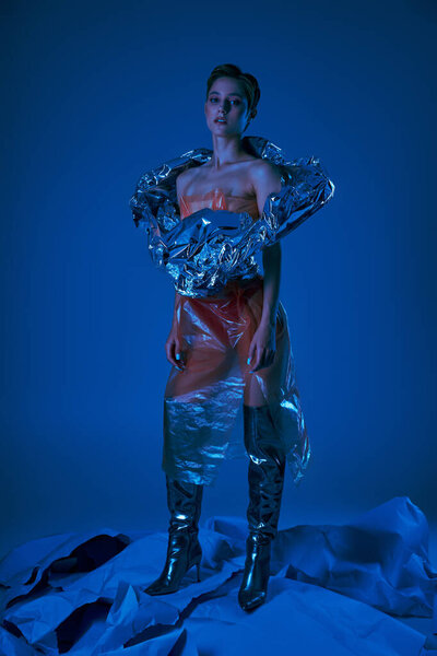 A woman poses in a unique and artistic outfit created from recycled materials.