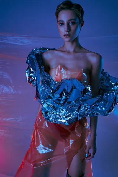 stock image A woman poses in a studio, wearing a stylish outfit made from repurposed plastic materials.