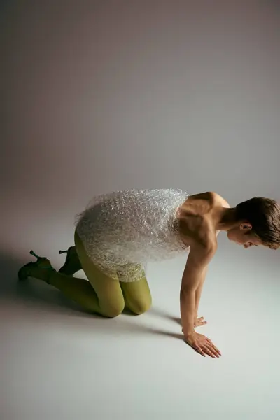 stock image A woman in a bubble wrap dress kneels on a white floor.