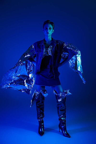 Woman in blue lit studio wears futuristic outfit of recycled materials