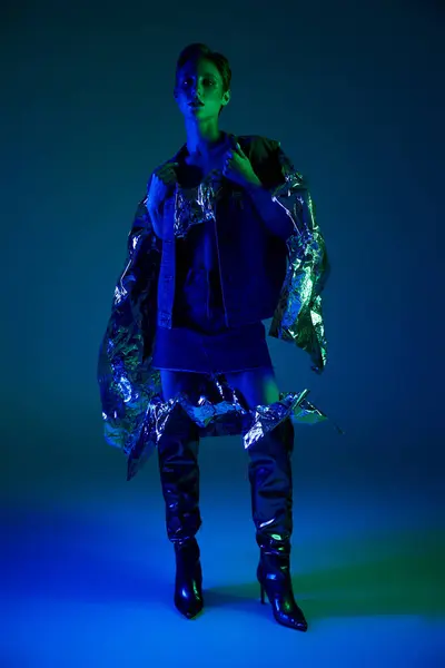 Stock image A woman poses in a blue and silver outfit under neon lights.