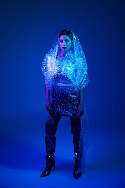 Woman confidently wears bubble wrap dress in studio, showcasing sustainable fashion beauty