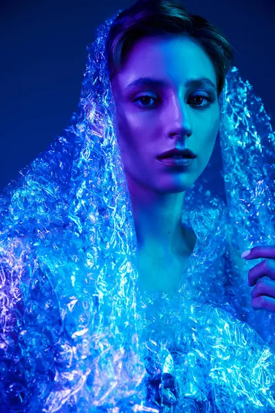 stock image A woman enveloped in blue light, with her face partly hidden by a bubble wrap veil.