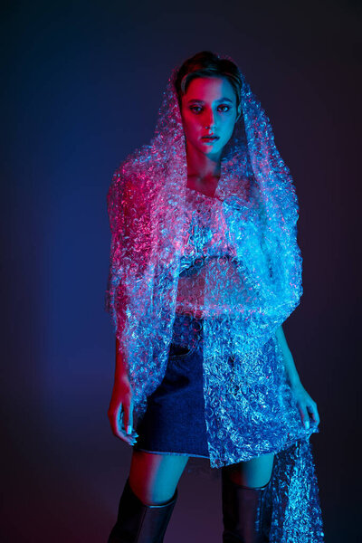 A woman stands in a blue and red light, wearing bubble wrap as a fashion statement.
