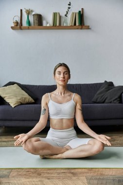 Vitiligo 'su olan genç bir kadın modern bir dairede yoga yapıyor, özenli meditasyonla huzur ve iç gücünü buluyor..