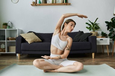Vitiligo 'su olan genç bir kadın modern dairesinde bir paspasla yoga yapıyor..