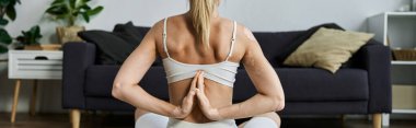 Vitiligo 'su olan genç bir kadın bir dairede yoga pozu veriyor, elleri arkadan kenetlenmiş..