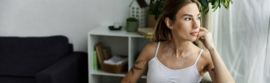 Vitiligo 'su olan genç bir kadın modern bir dairede yoga yapıyor. Bir anlık meditasyon ve kendini düşünme anında pencereden dışarı bakıyor..