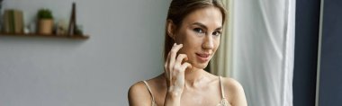Vitiligo 'su ve dövmesi olan genç bir kadın rahat yatak odasında kameraya gülümsüyor..