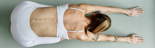 A young woman in active wear practices yoga in a modern apartment, focusing on meditation and mental wellbeing.