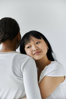 Asyalı bir kadın başını Afrikalı Amerikalı bir kadının omzuna koyar..