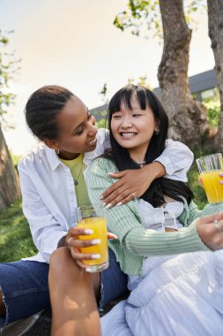 Lezbiyen bir çift, güneşli bir günde pikniğin tadını çıkarır, güler ve bir şeyler içerler..