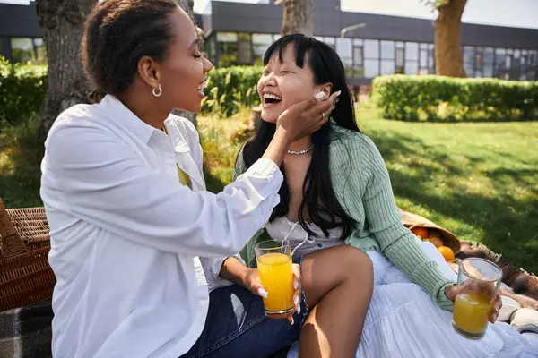 Stock image Two women share a tender moment during a picnic, their laughter echoing through the sunny day.